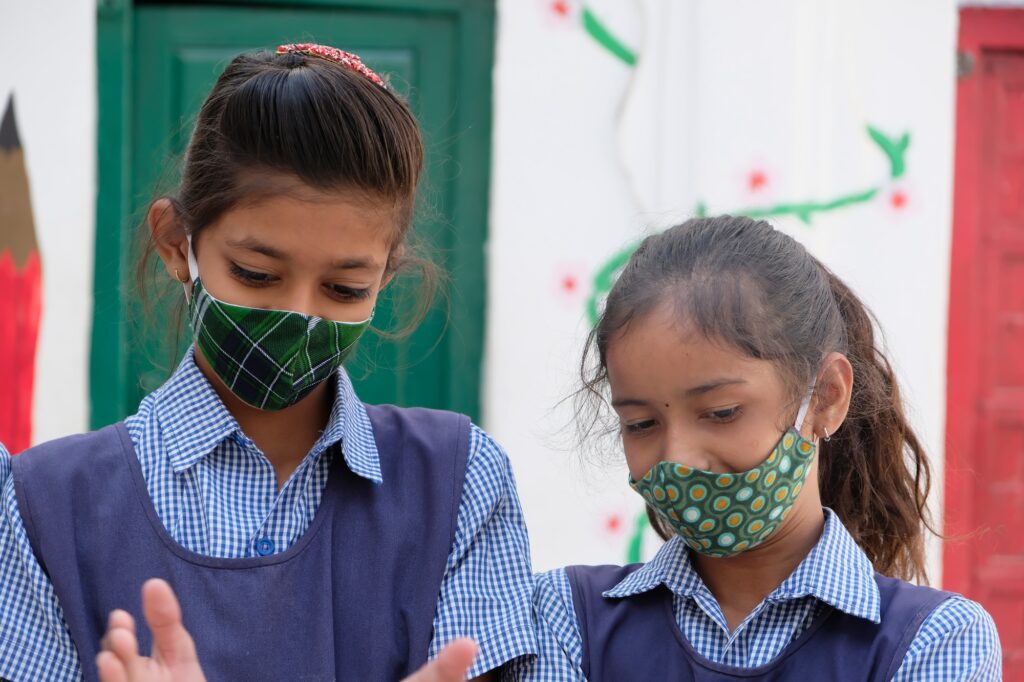 Cute Indian schoolgirls in face masks and uniforms at school during Covid-19